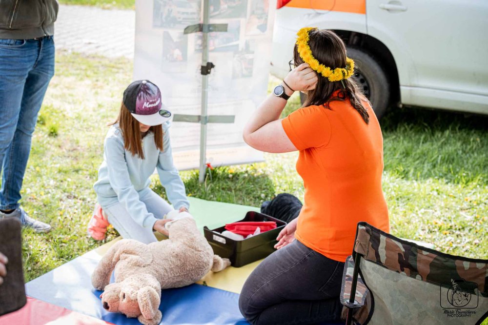 Dívka trénuje první pomoc na plyšovém psovi při venkovní akci